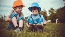  Two kids reading a book in a field
